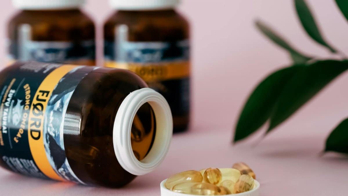 Close-up of omega-3 capsules and bottles on a pink background, ideal for health and wellness themes.