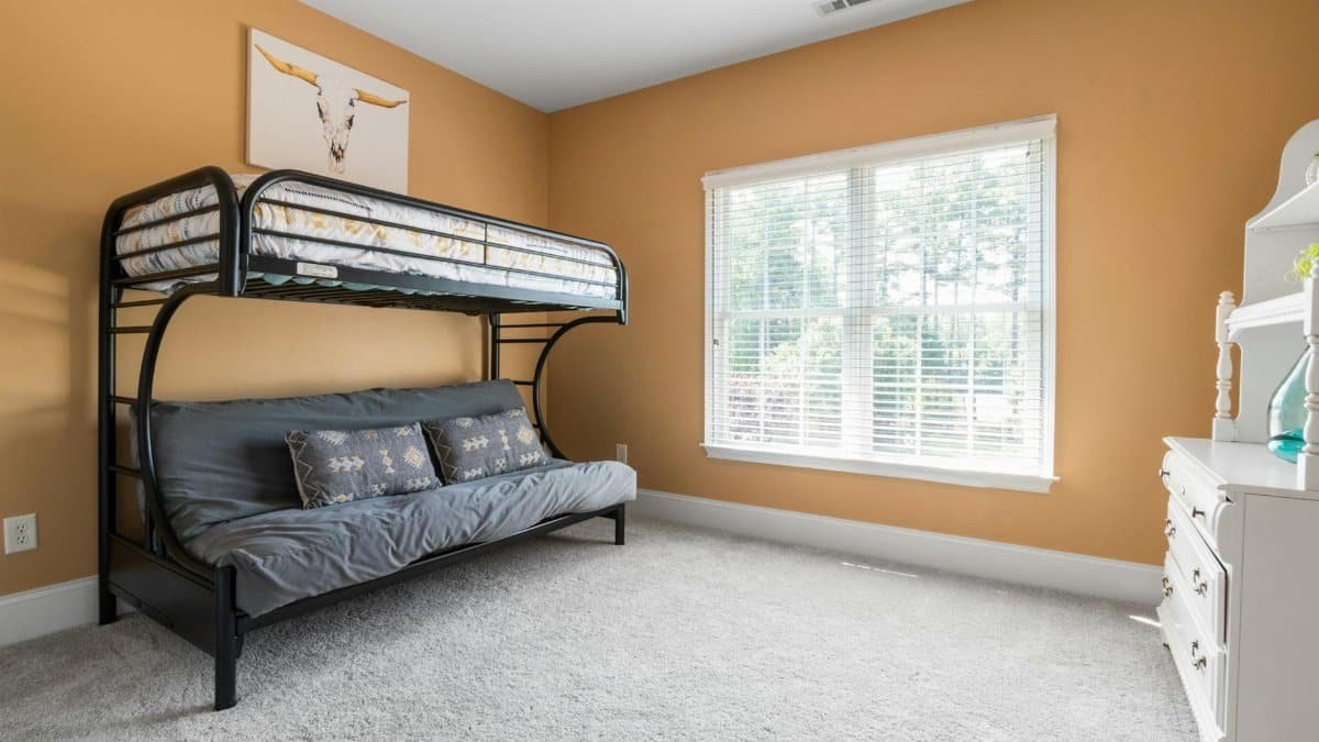 A bright bedroom with a modern bunk bed, large window, and stylish decor.