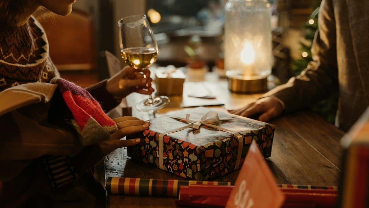 Warm holiday atmosphere with gift exchange and wine, perfect for festive moments.