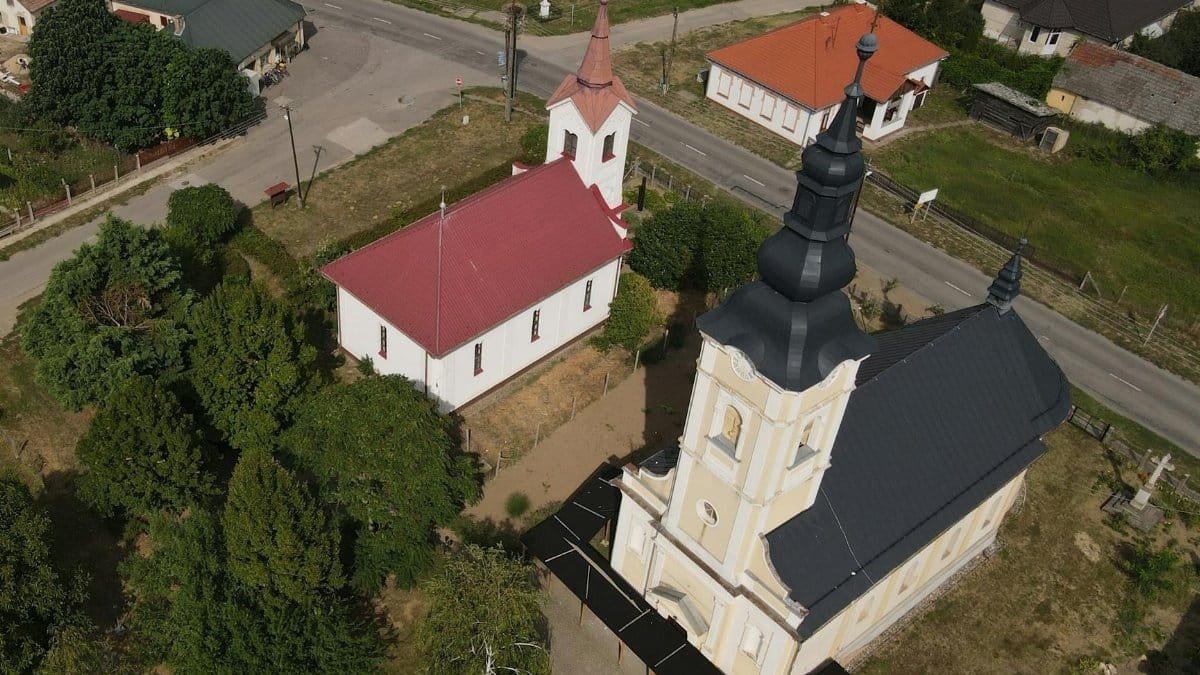 Drone shot of churches in Aranyosapáti, Hungary, showcasing architectural contrast.