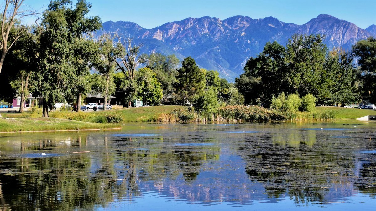 Beautiful lake reflection of the Wasatch Range in Salt Lake City, Utah, surrounded by lush greenery.