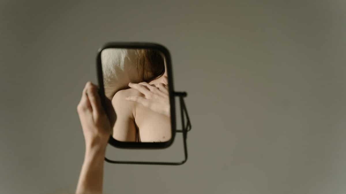 An artistic reflection of a woman gazing at herself in a mirror. Minimalist and thought-provoking.