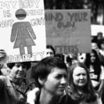 A black and white image of a protest with signs advocating for body autonomy and reproductive rights.