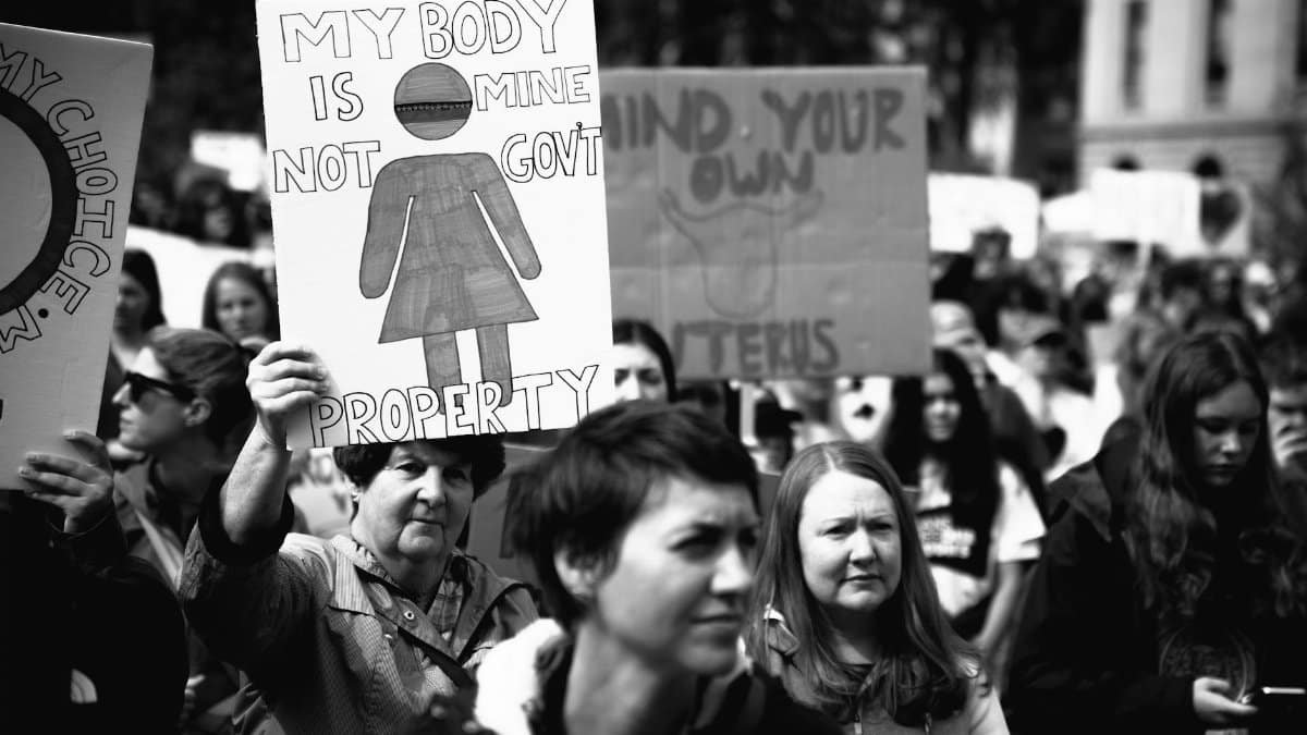 A black and white image of a protest with signs advocating for body autonomy and reproductive rights.