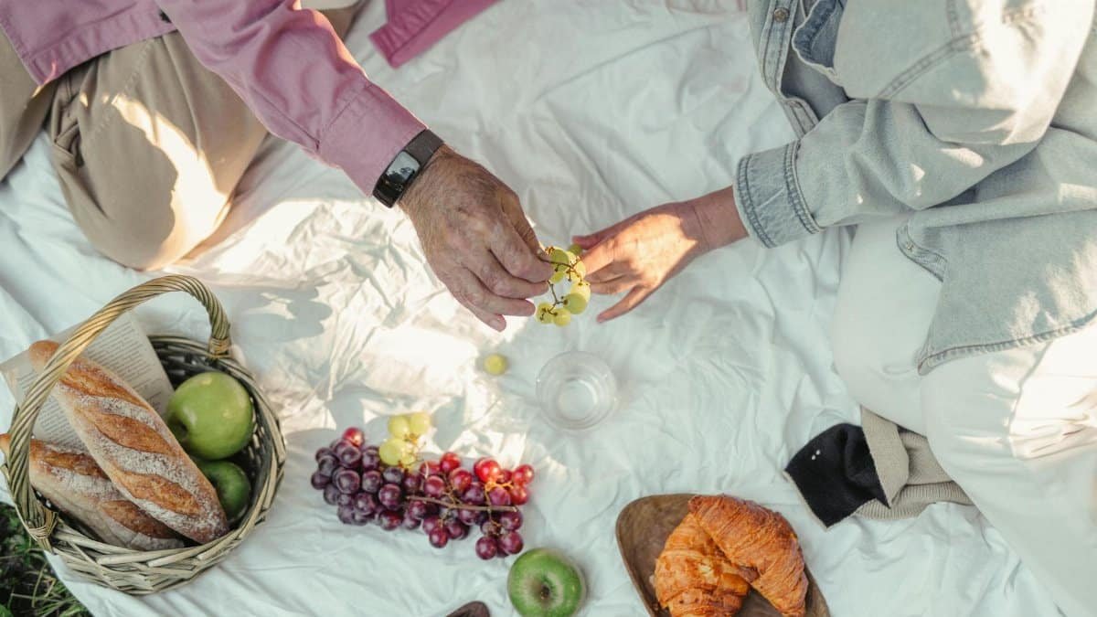 Top view of a relaxing picnic with fresh fruits, bread, and croissants.