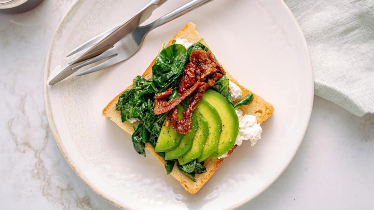 Savor this healthy avocado and spinach toast served on a marble table, perfect for breakfast.
