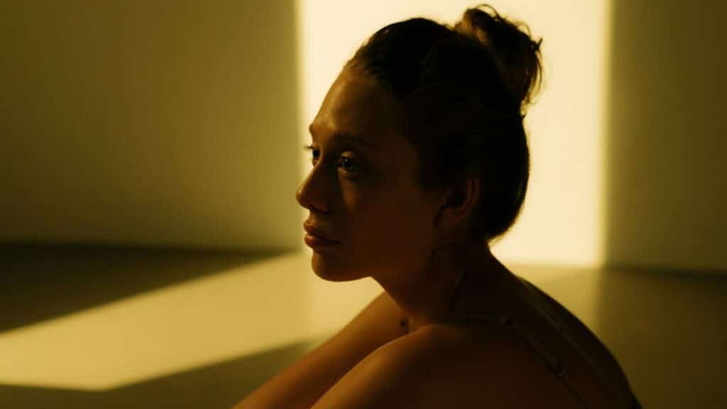 Side view of a woman reflecting in warm sunlight indoors, creating a serene and introspective mood.