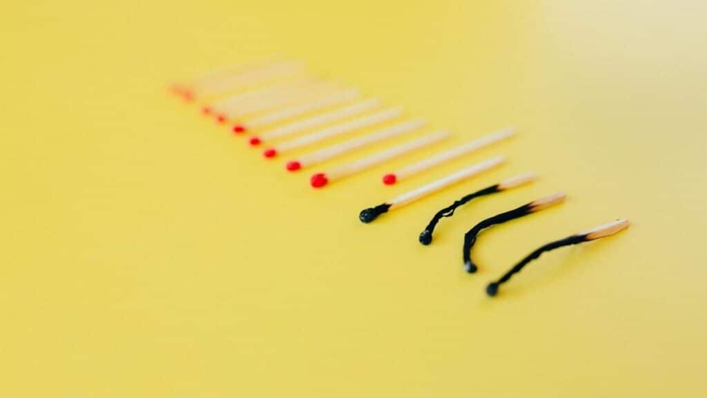 Symbolic representation of burnout using matches on a yellow background, illustrating exhaustion.