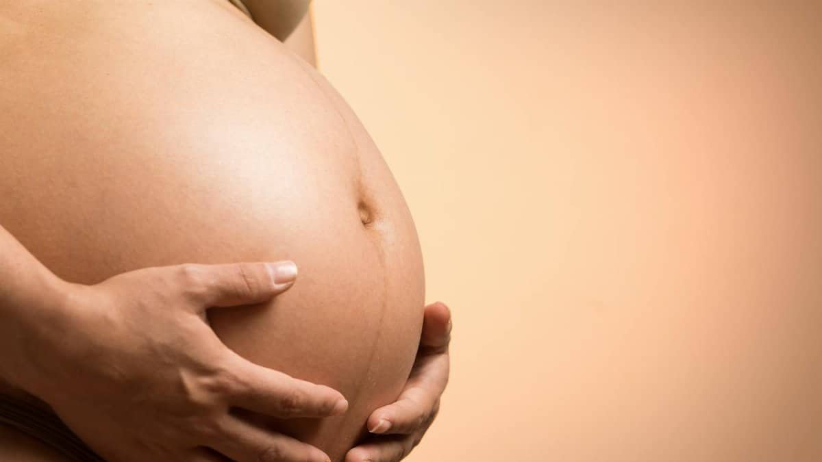 A tender close-up of a pregnant woman's hands holding her belly, symbolizing maternity and love.