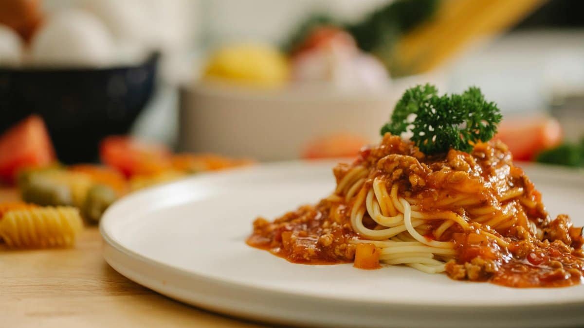 Delicious yummy spaghetti pasta with Bolognese sauce garnished with parsley and served on table in light kitchen