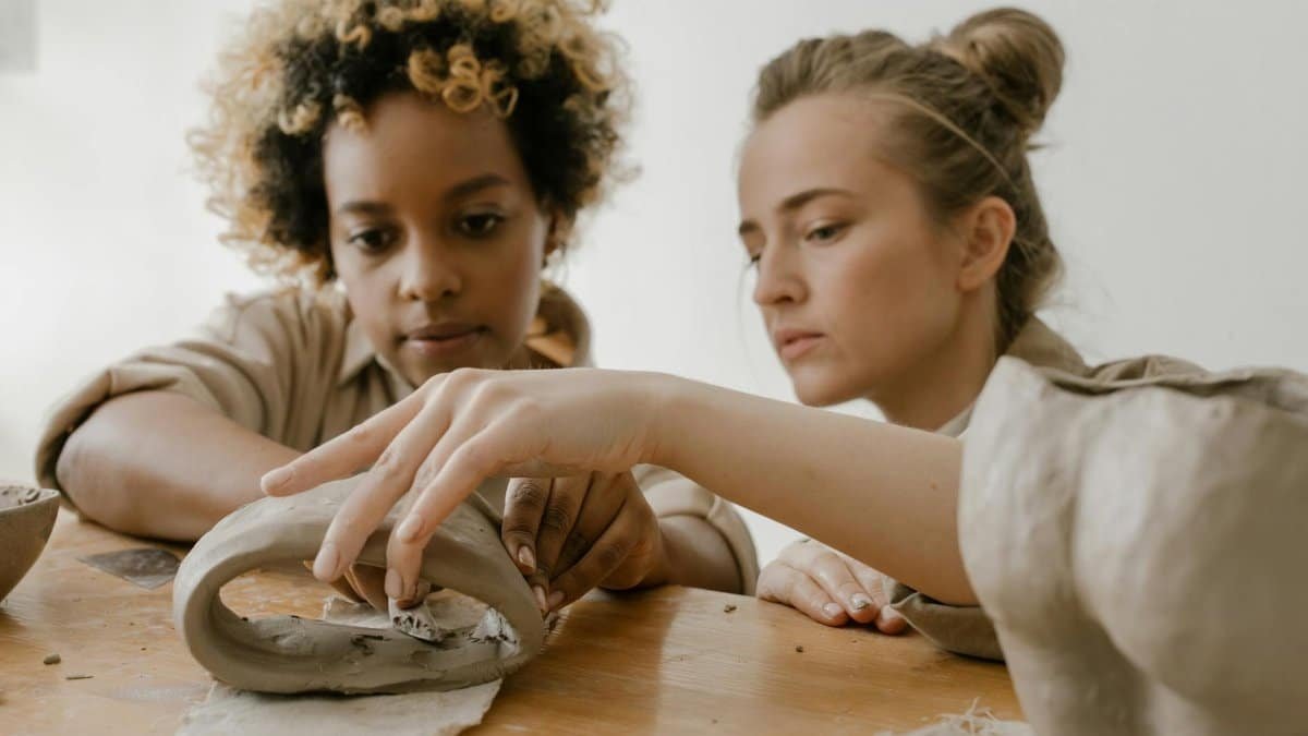 Two focused women crafting pottery pieces in a creative ceramics class.