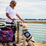 A senior woman enjoying a day by the water with her service dog in Detroit.