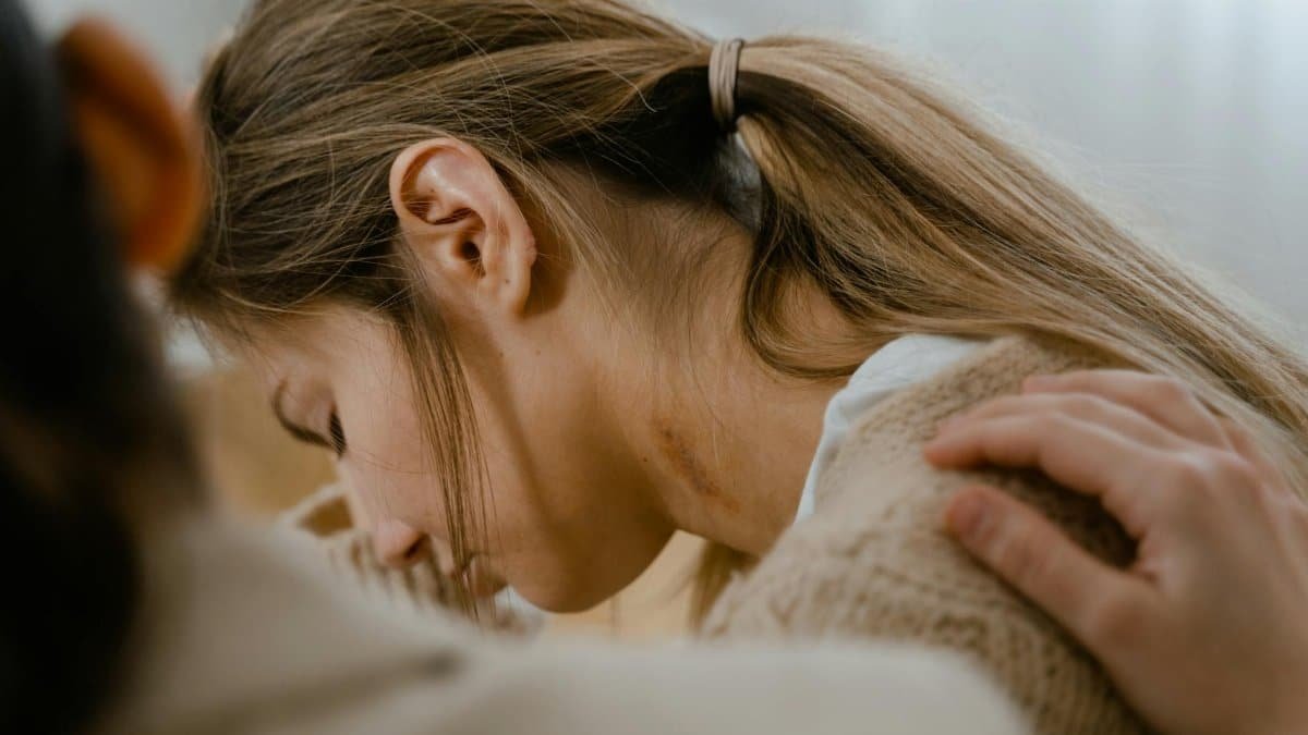 An emotional moment showing a comforting gesture with a hand on a woman's shoulder.