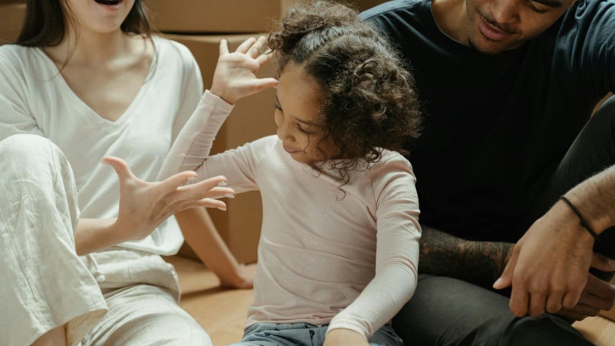 Family enjoying their new home, sitting among moving boxes and having a fun moment together.