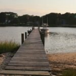 Serene wooden pier at sunset in Hampton Bays, NY, leading to calm waters.