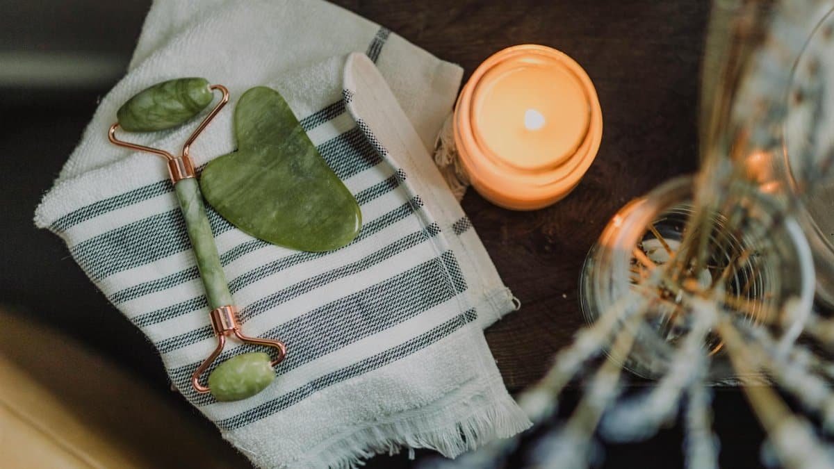 A serene spa setup featuring a jade roller, gua sha, towel, and candle for ultimate relaxation.