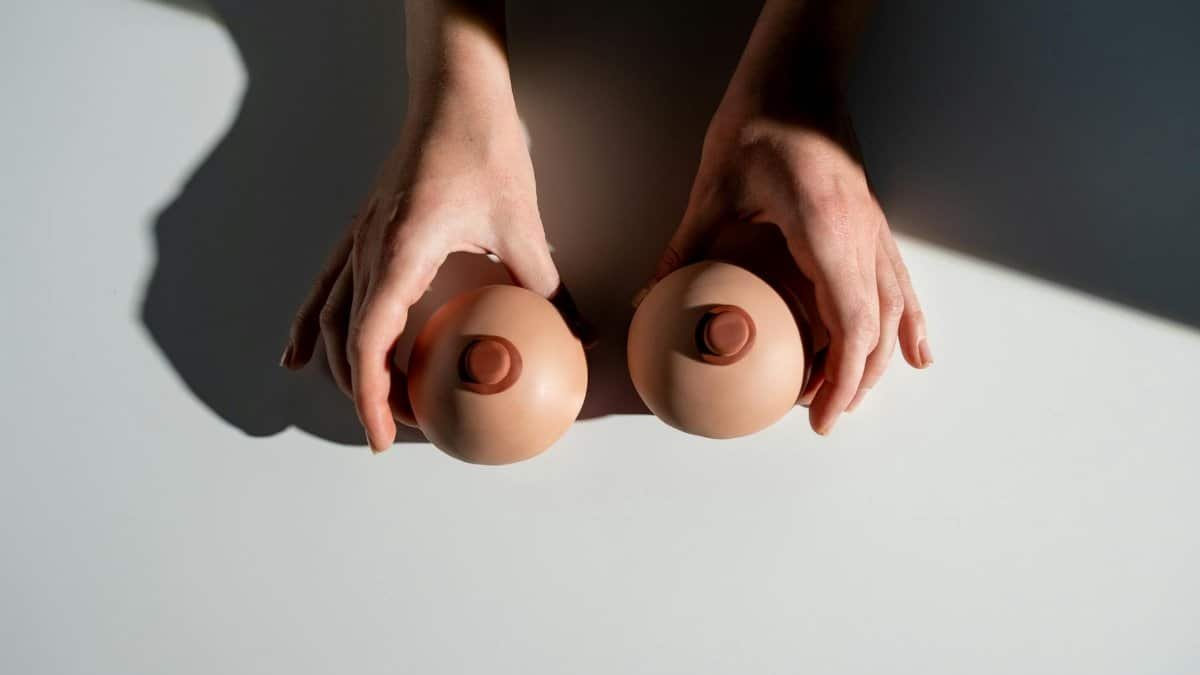 Artistic representation of breast health awareness using hands with model props under light.
