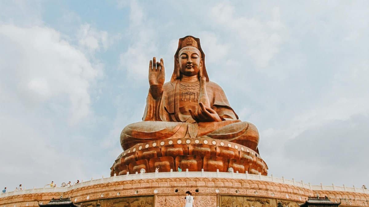 A grand Buddha statue in an outdoor temple setting with a cloudy sky backdrop, symbolizing peace and spirituality.