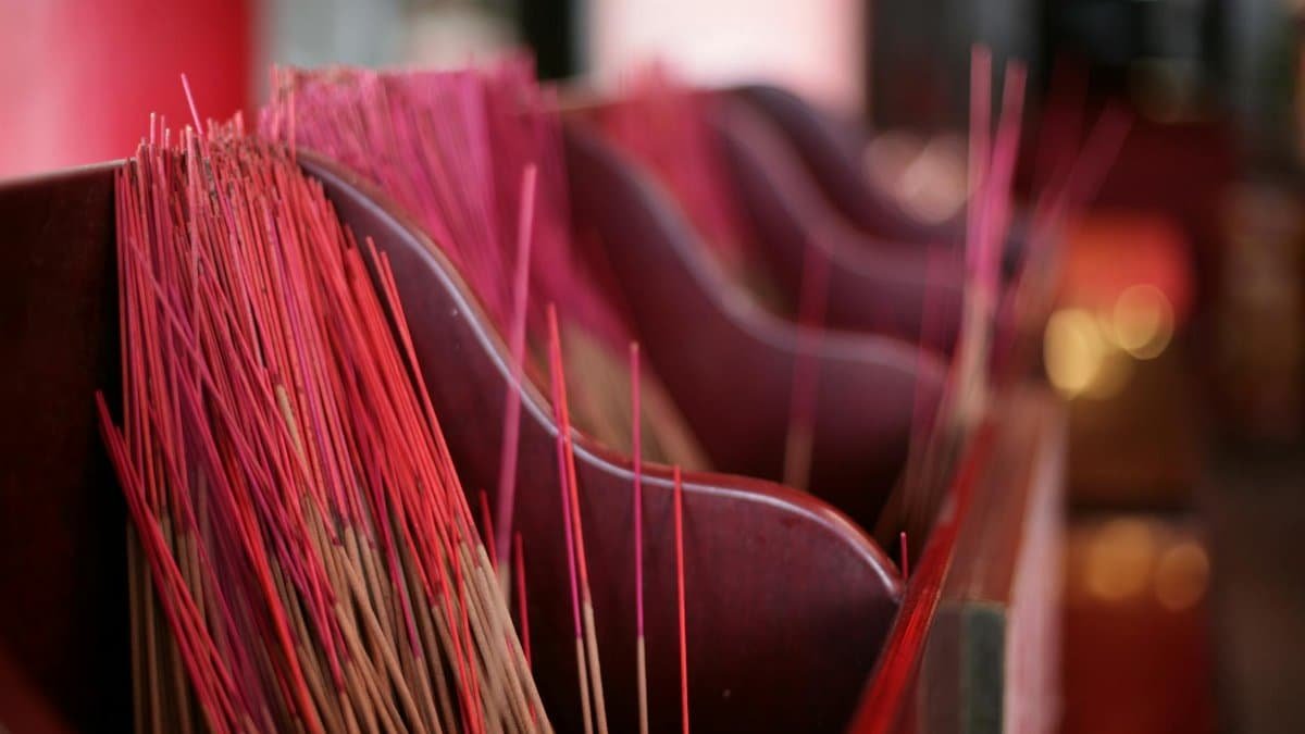 A detailed view of red incense sticks arranged in a wooden tray, creating a vibrant cultural ambiance.