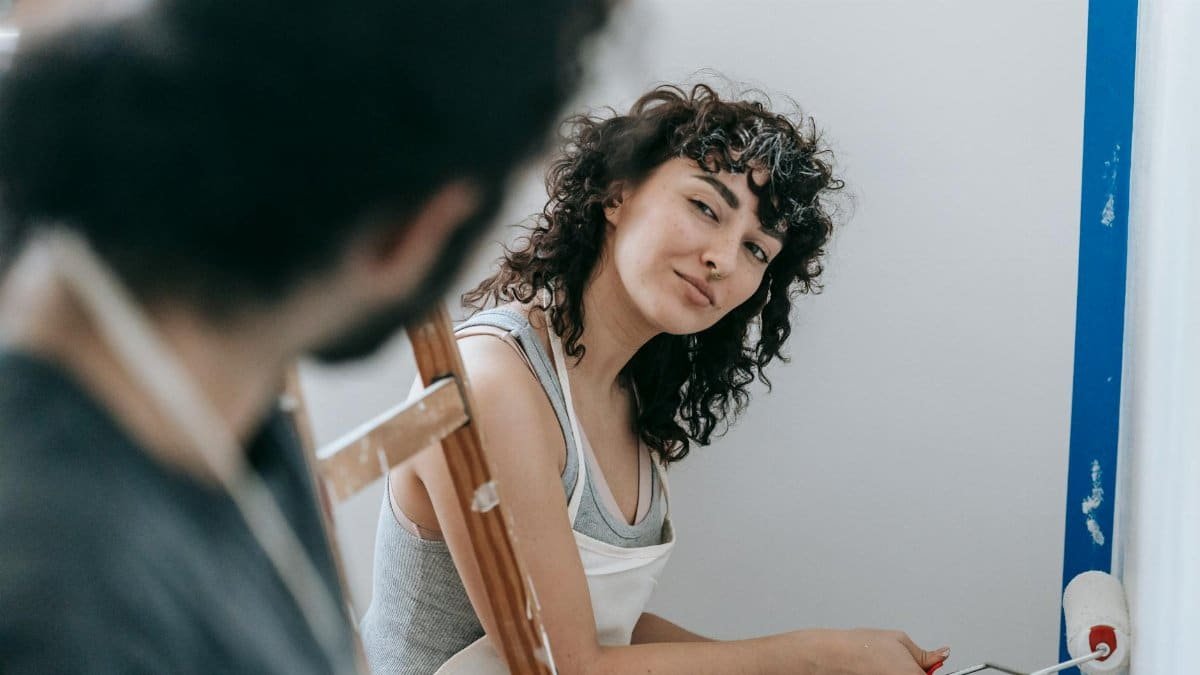 A couple enjoying painting their new home together, creating a vibrant and cozy space.