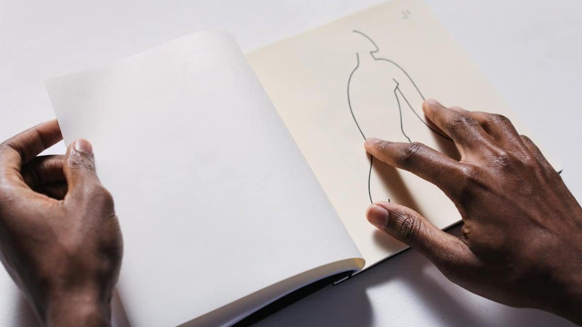 Close-up of hands interacting with a tactile art drawing on a sketchbook page.