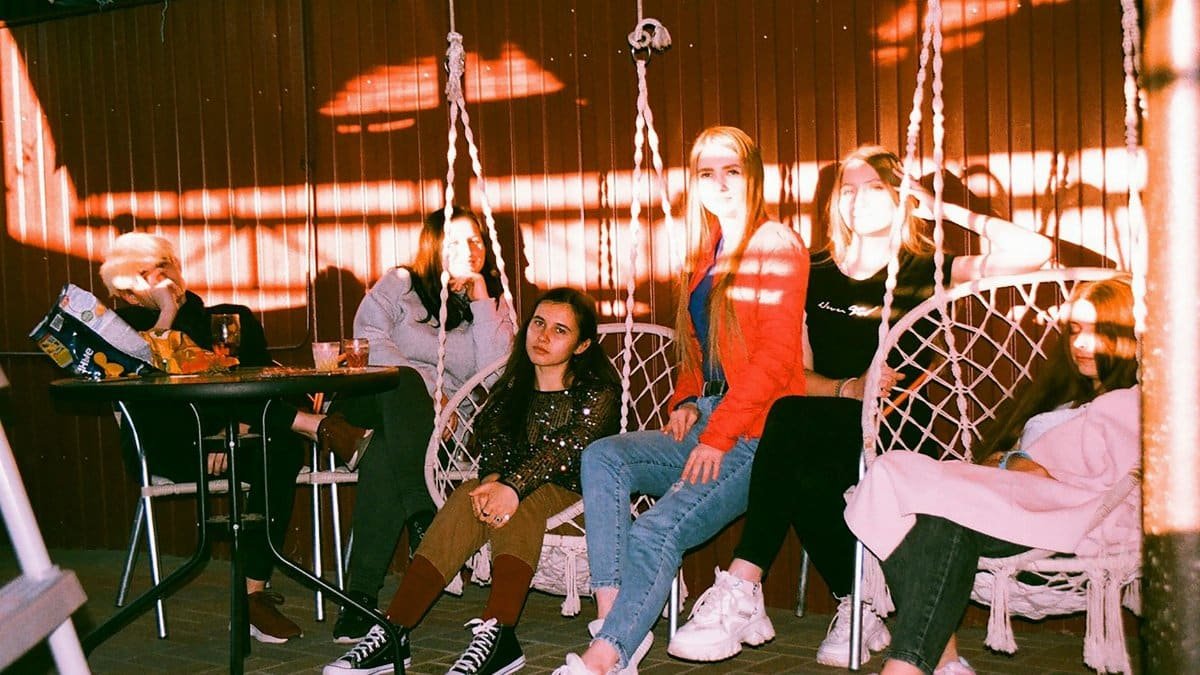 Young adults enjoying a casual evening sitting on swinging chairs outdoors.