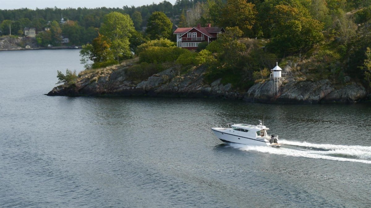 A motorboat cruises near a picturesque island with a charming cottage, ideal for travel and nature themes.