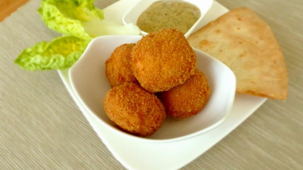 A delicious plate of crispy chicken bites served with sauce, crispy bread, and fresh lettuce.