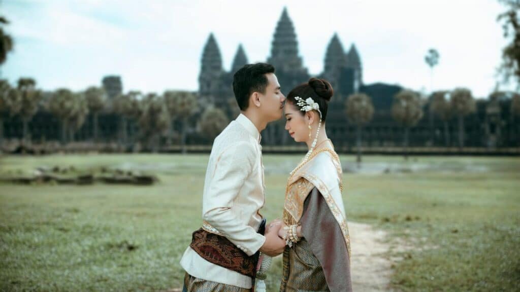A couple in traditional Cambodian attire embracing at Angkor Wat, a symbol of timeless love.