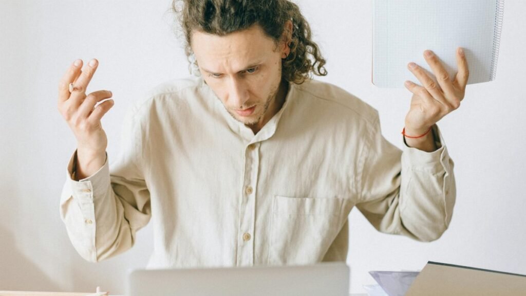A frustrated man at his desk showing signs of exhaustion and stress in an office setting.