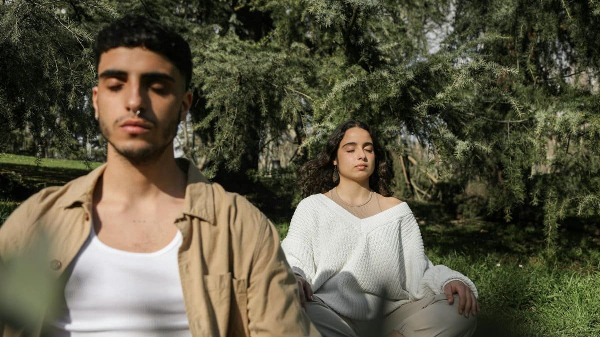 Two adults practicing meditation in a tranquil forest setting, promoting relaxation and mindfulness.