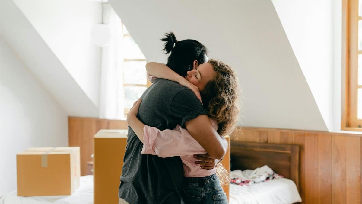 Young couple hugging in their new home, surrounded by boxes, symbolizing a fresh start.