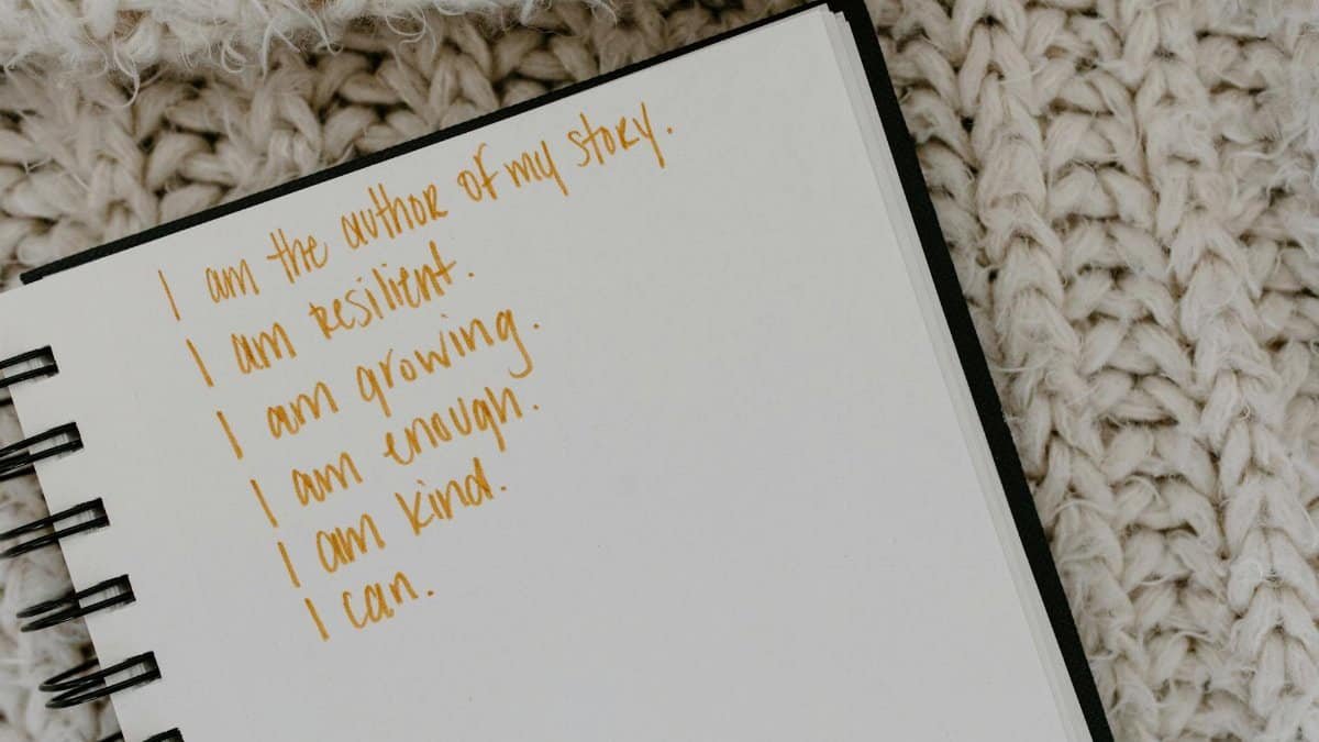 Notebook with handwritten affirmations on knitted fabric background.