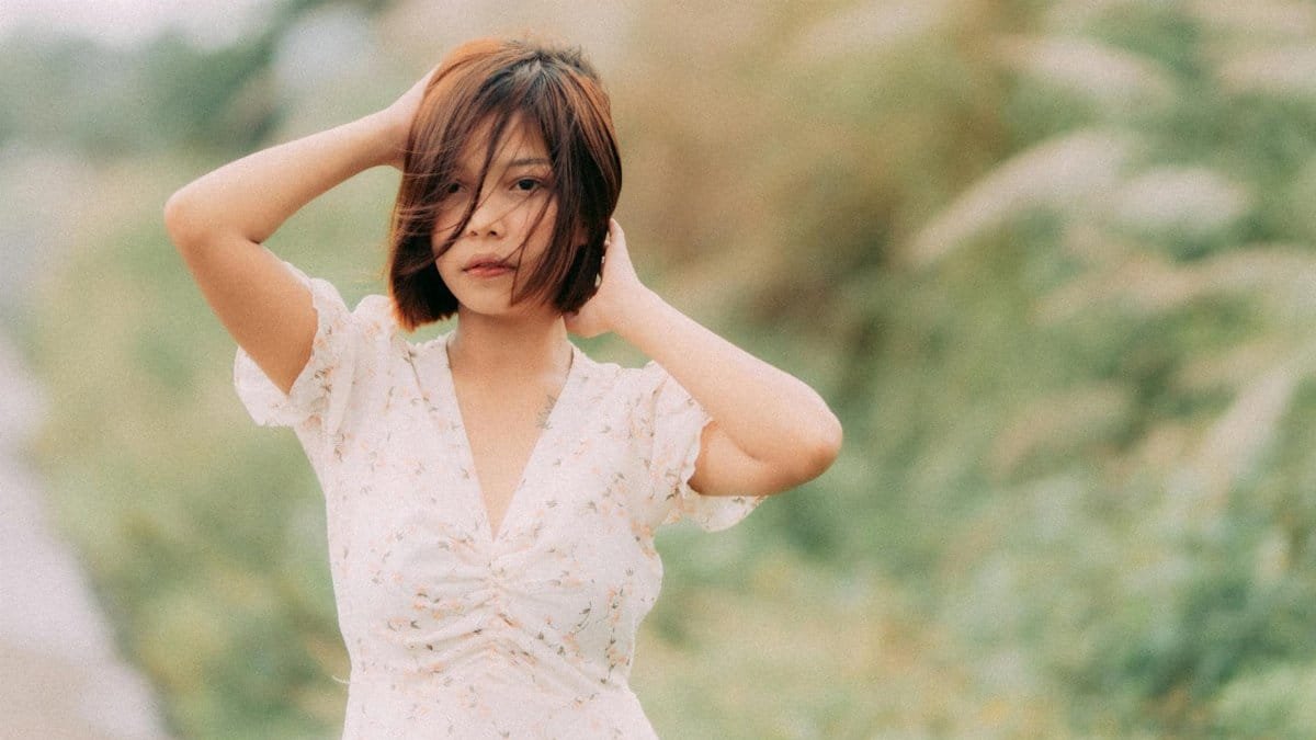 A serene portrait of a woman with short hair outdoors, exuding a calm and peaceful mood.