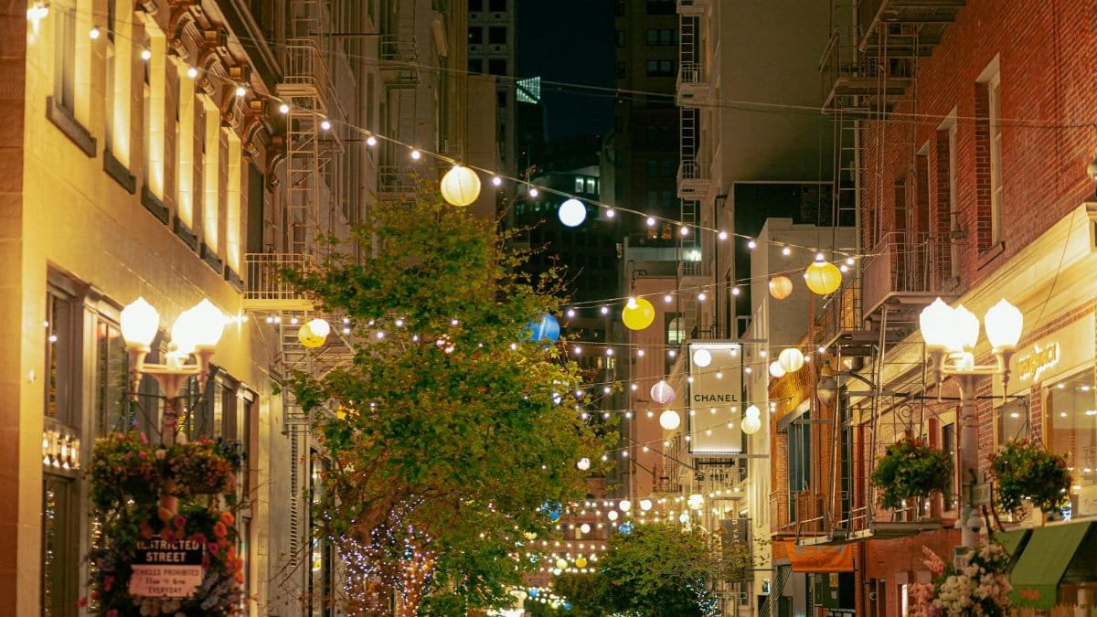 Illuminated street in San Francisco with cafe lights and historic architecture.