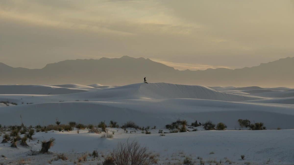 Lonely figure walking on the majestic White Sands dunes in New Mexico during sunset.