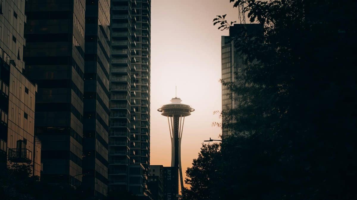 The Space Needle framed between modern skyscrapers at sunset in Seattle.
