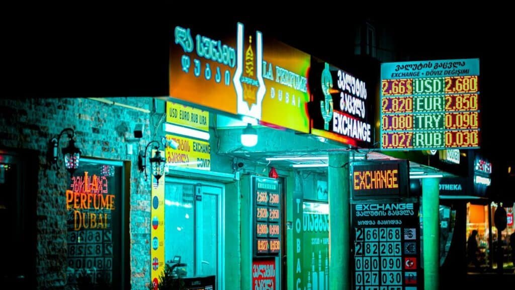 Night view of a brightly lit storefront and currency exchange signs in Batumi, Georgia.