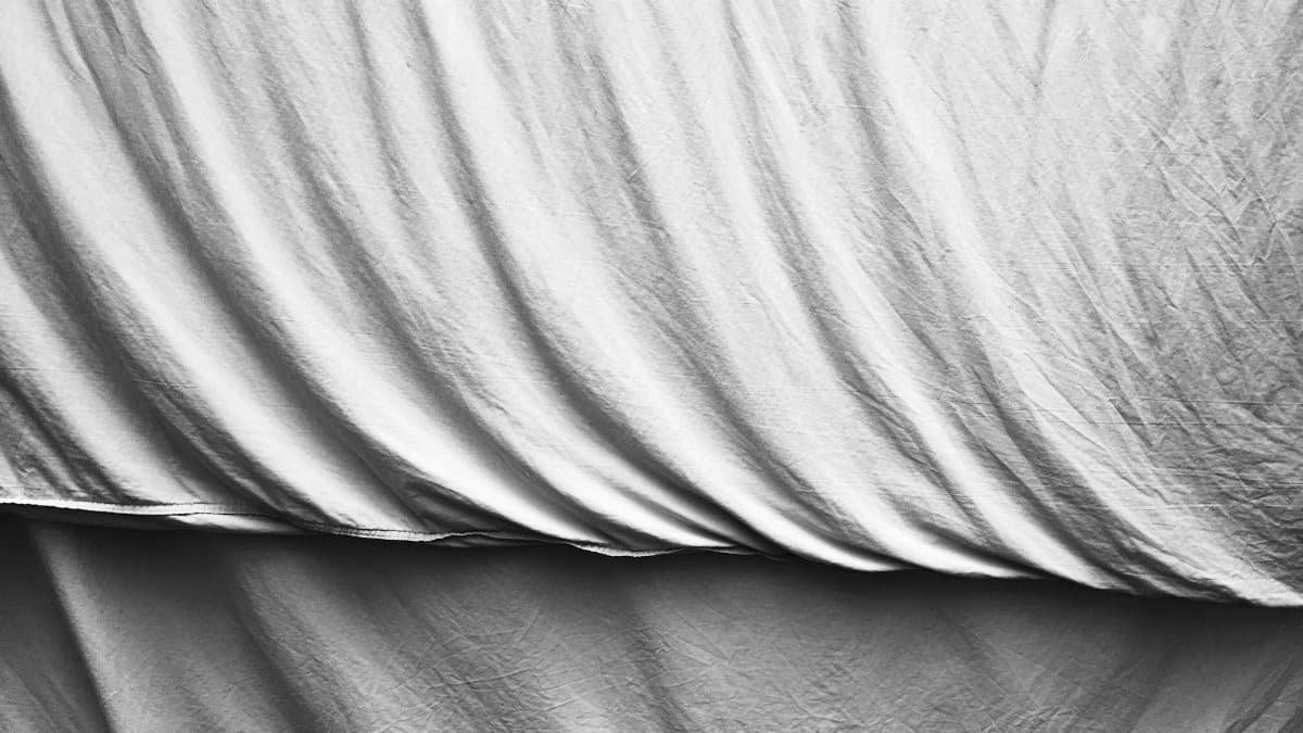 Close-up of soft, white bedding fabric draped naturally in a minimalist style.