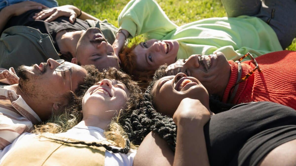 A diverse group of friends laughing and bonding together in a sunny outdoor setting.