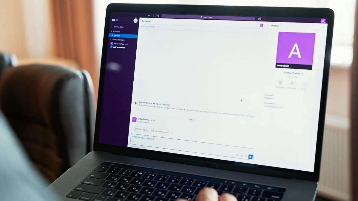 Person using a laptop with an online communication platform, showcasing modern work tech.