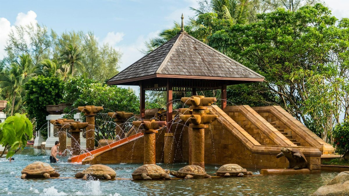 Elegant fountain at a tropical resort featuring turtle statues and lush greenery.