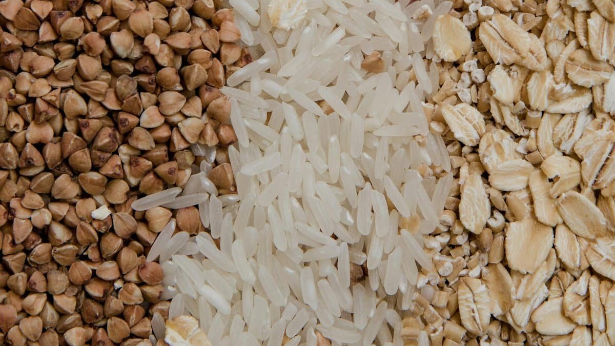 Close-up of assorted raw grains including buckwheat, rice, and oats, highlighting healthy food choices.