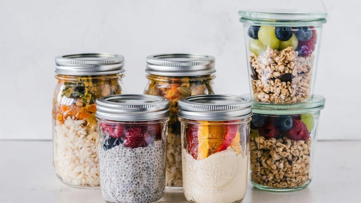 Close-up of healthy food jars containing granola, fruits, and yogurt.