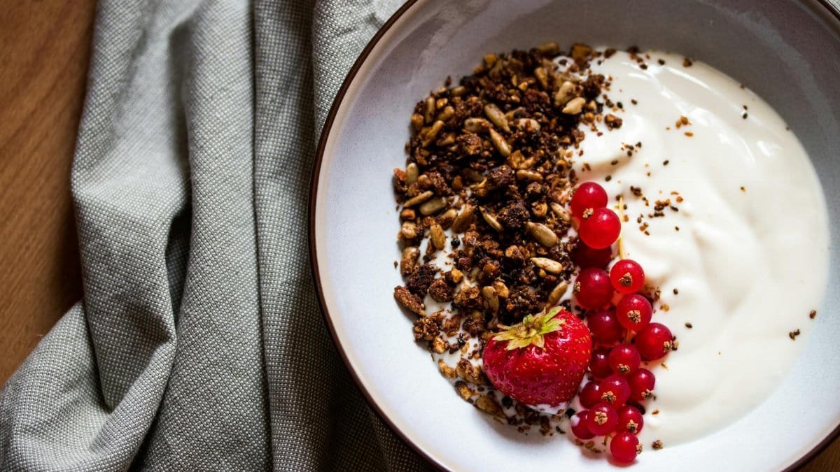 Delicious breakfast bowl featuring yogurt, granola, strawberry, and red currants, perfect for a healthy start.