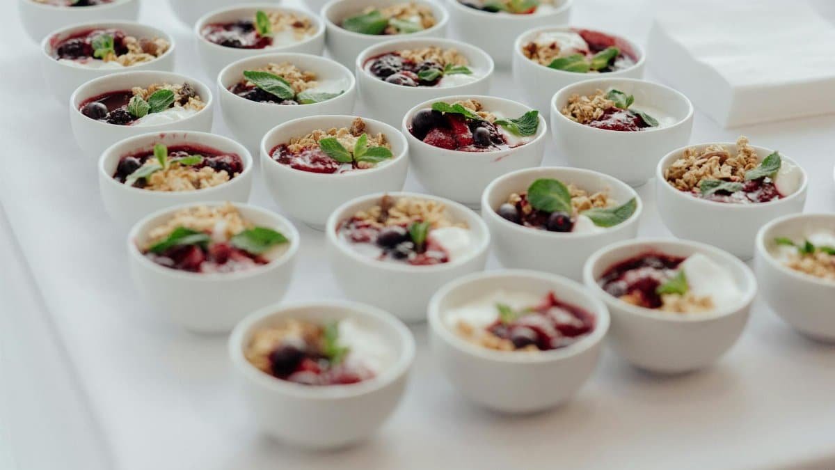 Rows of delicious yogurt parfaits topped with granola and fresh berries, perfect for a breakfast buffet.