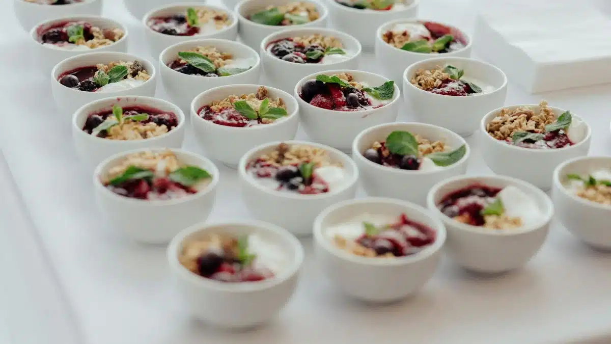 Rows of delicious yogurt parfaits topped with granola and fresh berries, perfect for a breakfast buffet.