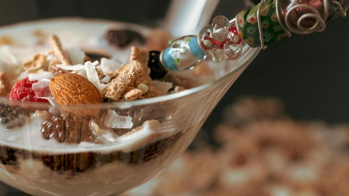 Delicious yogurt parfait with granola, almonds, and raspberries in a glass cup.