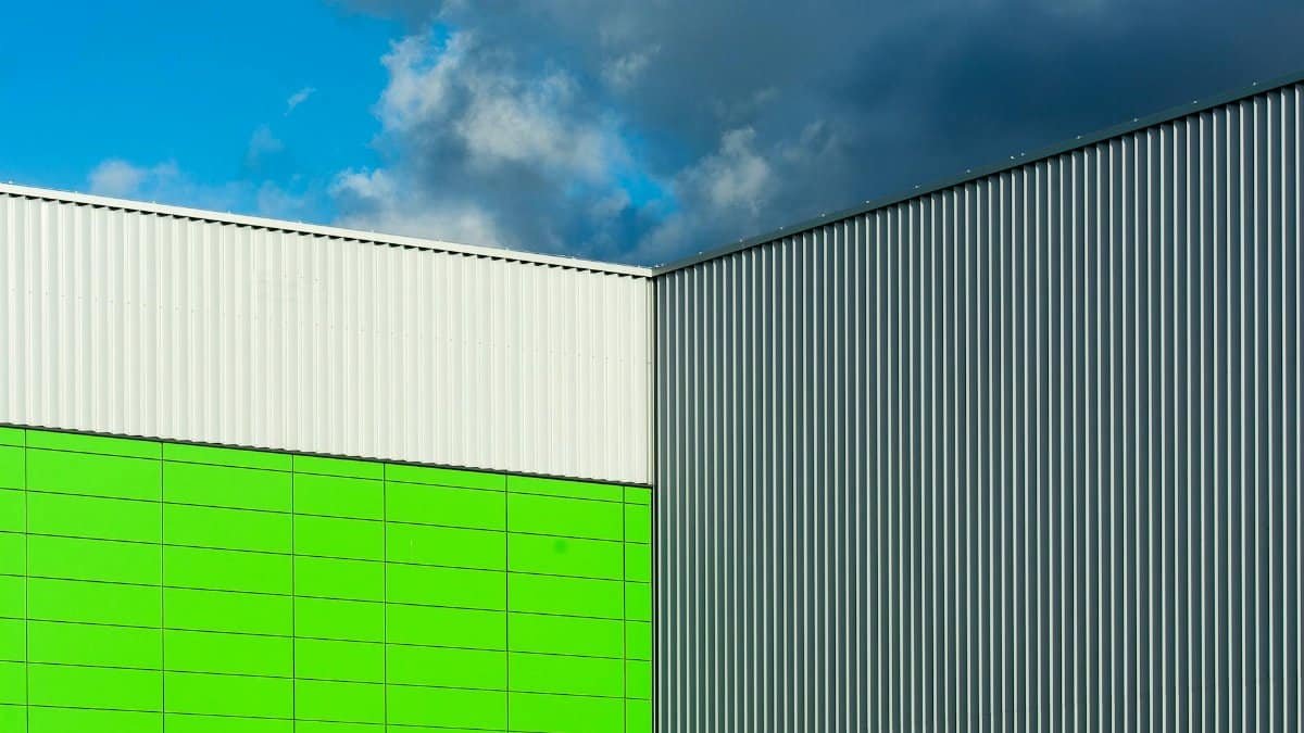 Close-up of a modern building facade with colorful panels and corrugated metal against a dramatic blue sky.