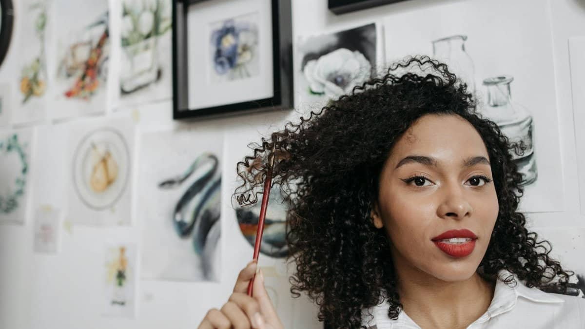A woman holding a paintbrush in an art studio surrounded by watercolor paintings. Inspiring and creative atmosphere.